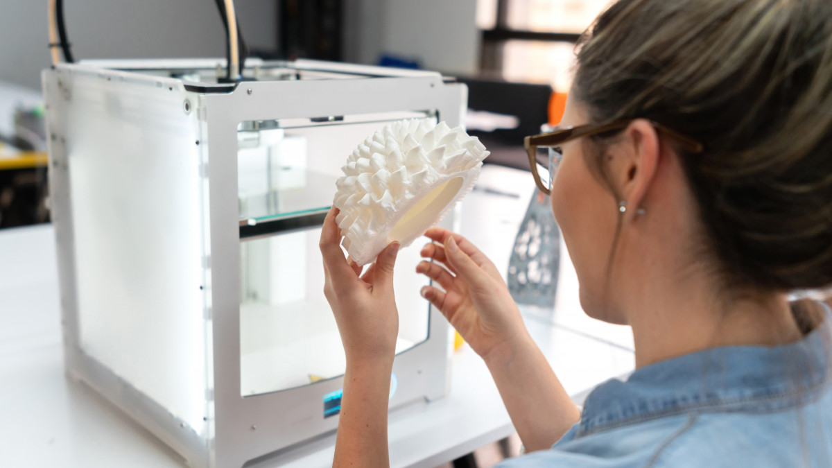 Portrait of a woman using a 3D printer at a workshop - technology concepts