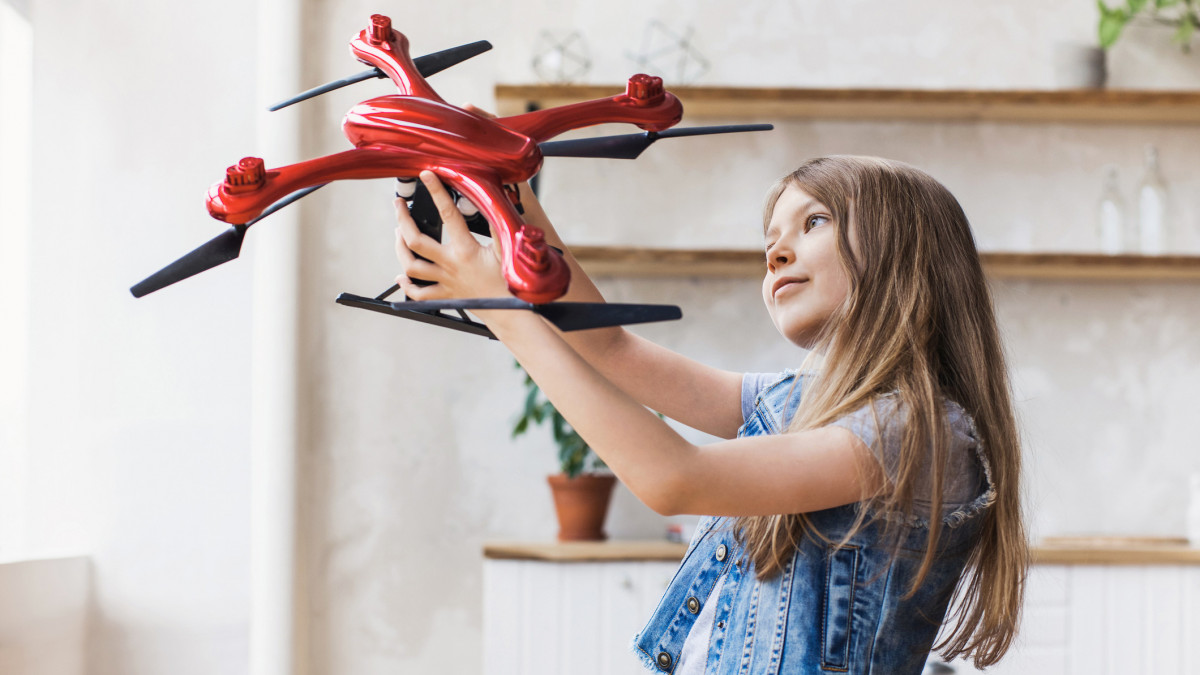 Young cute girl exploring quadcopter. Education, future, children, technology, science and modern people concept