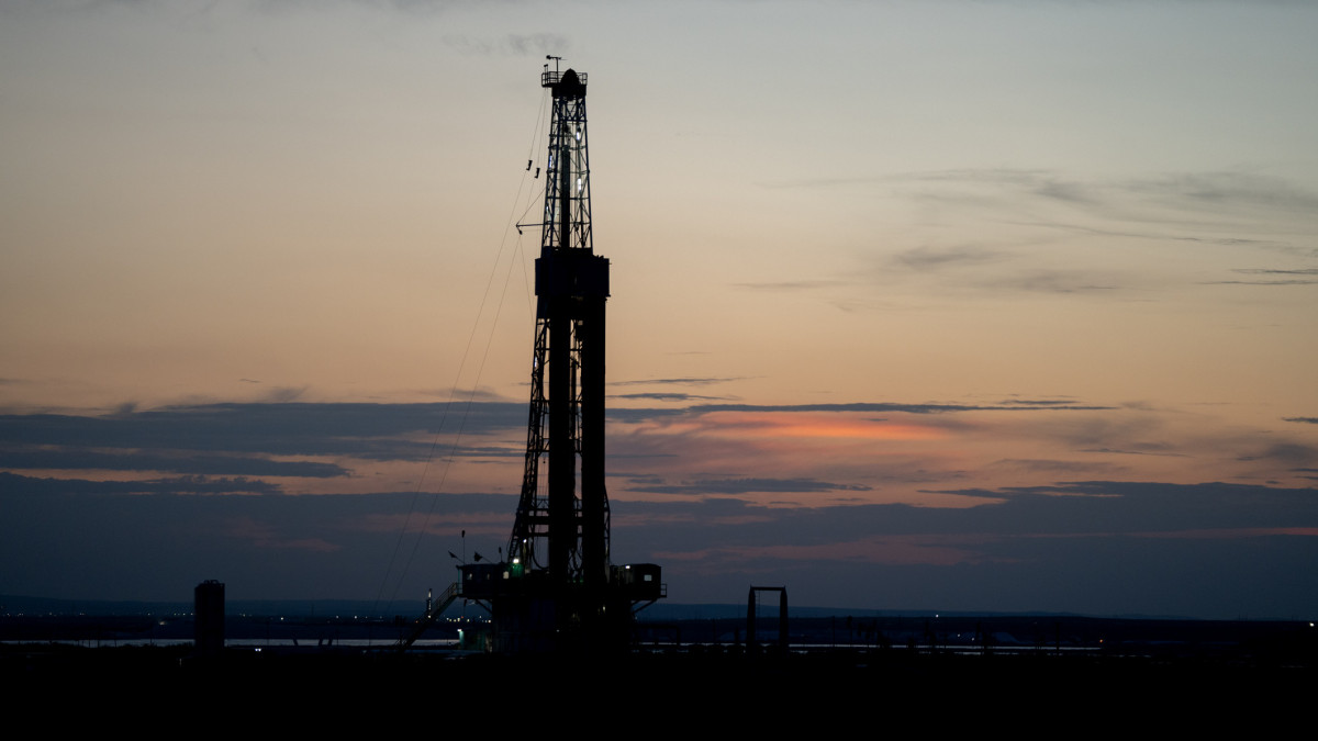 Fracking Drilling Rig Creating Gas or Oil Well Silhouetted at Dusk Under a Dramatic Sunset Sky