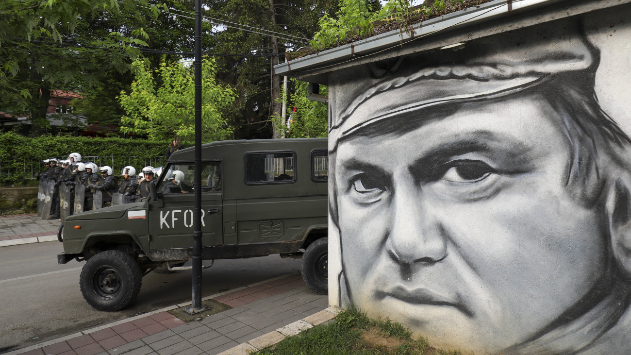 A NATO parancsnoksága alatt működő koszovói békefenntartó haderő, a KFOR katonái őrt állnak a népirtás, valamint háborús és emberiesség elleni bűncselekmények miatt 2017-ben életfogytiglani börtönbüntetésre ítélt Ratko Mladic volt boszniai szerb hadseregparancsnokot ábrázoló falfestmény  közelében az észak-koszovói Zvecanban 2023. május 29-én. A KFOR katonái három észak-koszovói településre vonultak ki, hogy megakadályozzák a helyzet romlását, miután a rendőrség és a helyi szerbek összecsaptak egymással. A szerbek tiltakozása 26-án kezdődött, amikor Zvecan, Leposavic és Zubin Potok újonnan megválasztott, albán nemzetiségű polgármesterei megpróbálták elfoglalni hivatalaikat, de a helyi szerbek nem akarták beengedni őket az önkormányzati épületekbe.