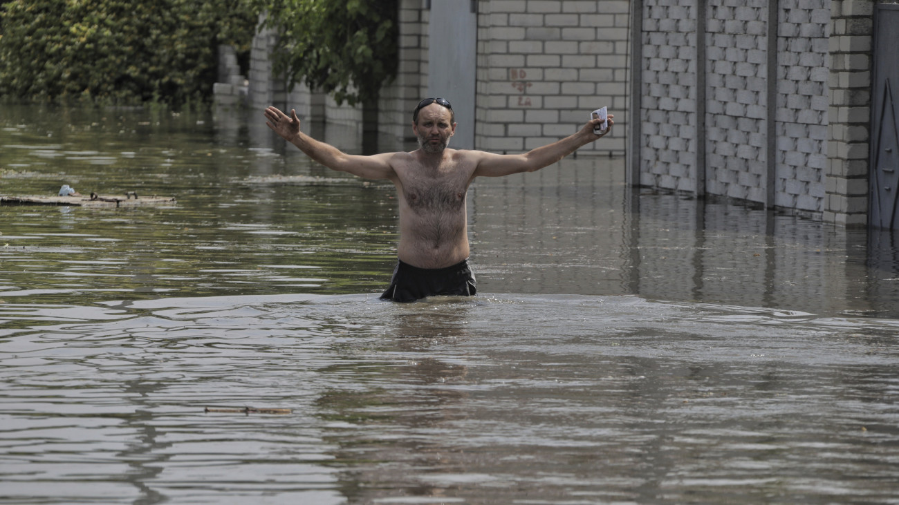Gátrobbantás miatt vízzel elöntött utcán egy férfi Herszonban 2023. június 6-án. Hajnalban robbanás történt a dél-ukrajnai Herszoni területen lévő, jelenleg orosz ellenőrzés alatt álló Nova Kahovka-i víztározójának gátján, az ukránok és az oroszok egymást vádolják a robbantás elkövetésével. Az ukrán belügyminiszter szerint mintegy 80 települést fenyeget árvíz.