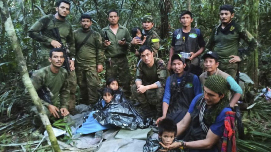 A kolumbiai  fegyveres erők sajtóhivatala által közreadott képen kolumbiai katonák és őslakosok megmentett gyermekek körül állnak az Amazonas tartománybeli Araracuara és a Guaviare tartománybeli San José del Guaviare városa közötti dzsungelben 2023. június 9-én. A négy gyerek 40 napja tűnt el egy kisrepülőgép-szerencsétlenséget követően. A legyengült állapotban lévő kiskorúakat először San Jose del Guaviaréba szállítják a helyi kórházba.