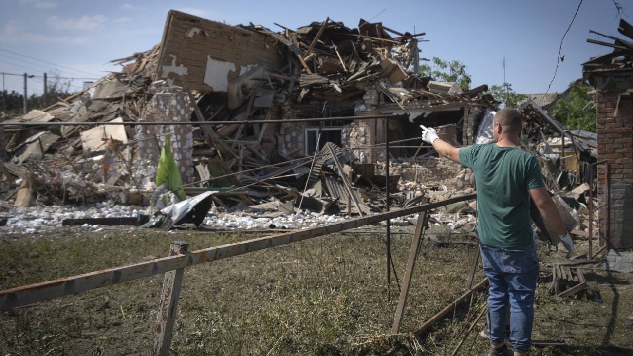 Egy férfi mutatja a szomszédja megsemmisült házát egy orosz légi támadást követően a kijevi régióban fekvő Sztari Petrivciben 2023. június 16-án.