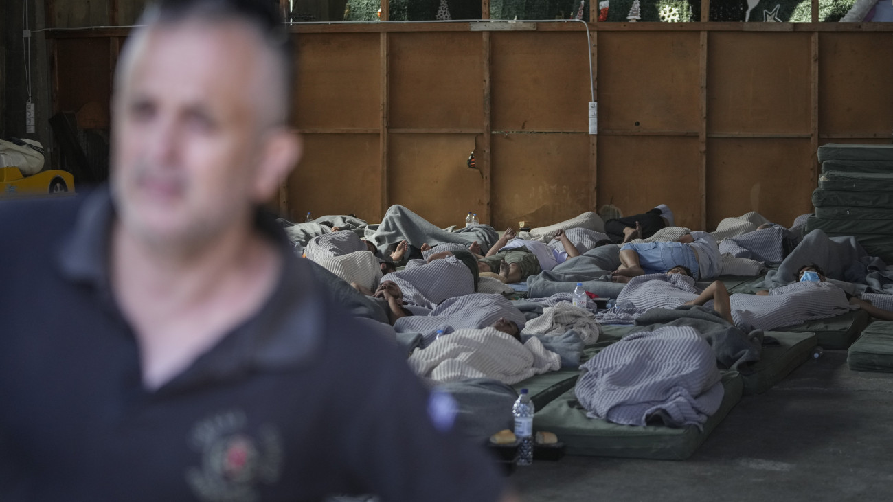 Túlélők alszanak a görögországi Kalamata kikötőjének egyik raktárában 2023. június 14-én, miután egy Líbiából Olaszországba igyekvő, több tucat illegális bevándorlót szállító halászhajó elsüllyedt a görög partok előtt. A hatóságok szerint legalább 78 ember életét vesztette, tucatnyian eltűntek, 104-et sikerült kimenteni.