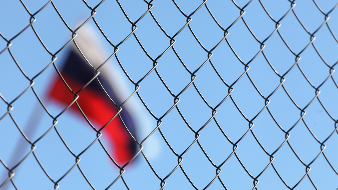 a fence of metal mesh behind which the Russian flag