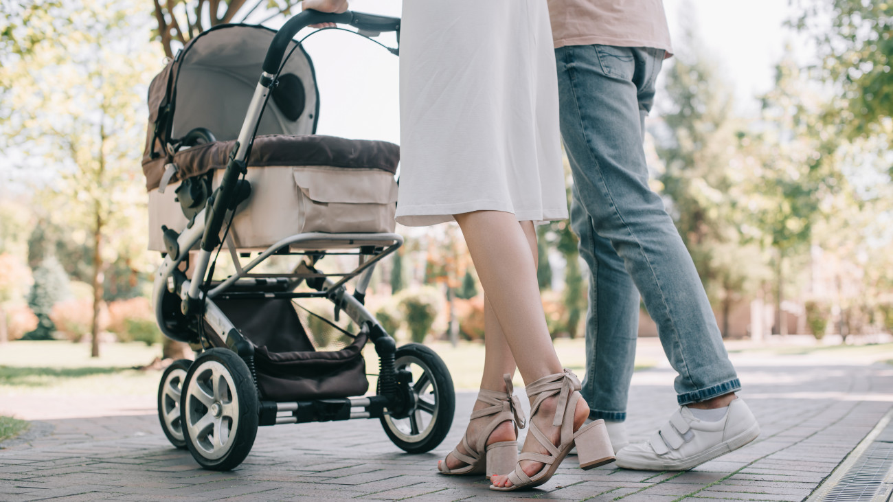 cropped image of parents walking with baby carriage in park