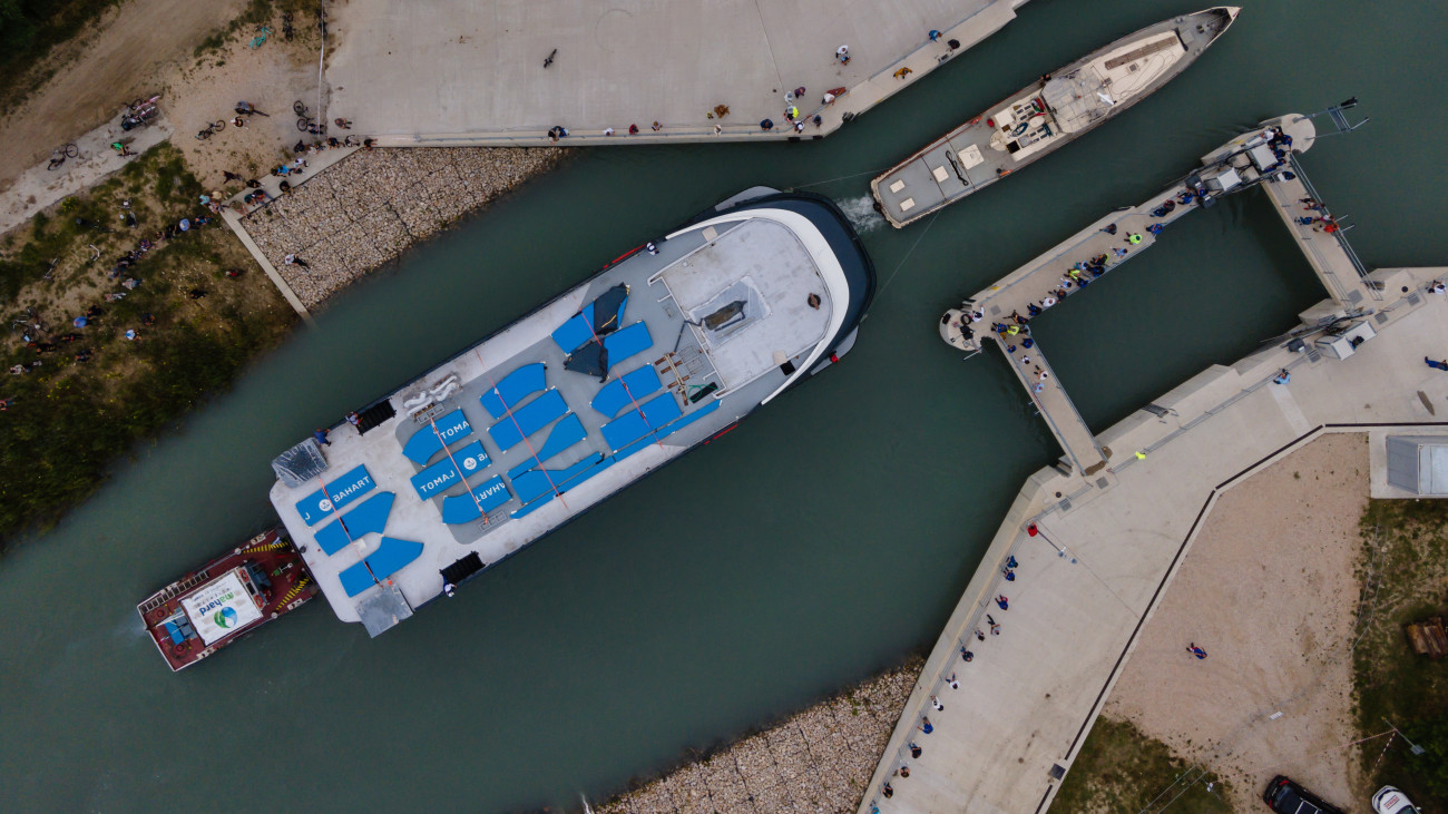 A drónnal készült felvételen a Balatoni Hajózási Zrt. (Bahart) egyik új kompját vontatják a Sió-csatorna balatonkiliti duzzasztógátjánál 2023. június 28-án. A Bahart a Magyar Turisztikai Ügynökség (MTÜ) közreműködésével építtetett két új személyhajója és két kompja 2021-ben készült el a komáromi hajógyárban, ahonnan egy héttel ezelőtt indultak útnak, hogy a Dunán lehajózva a Sió-csatornán keresztül elérjék a Balatont.