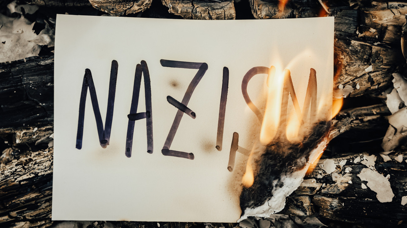 The word Nazism on white paper burning in a flame of fire. The concept of discrimination and problem of fascism