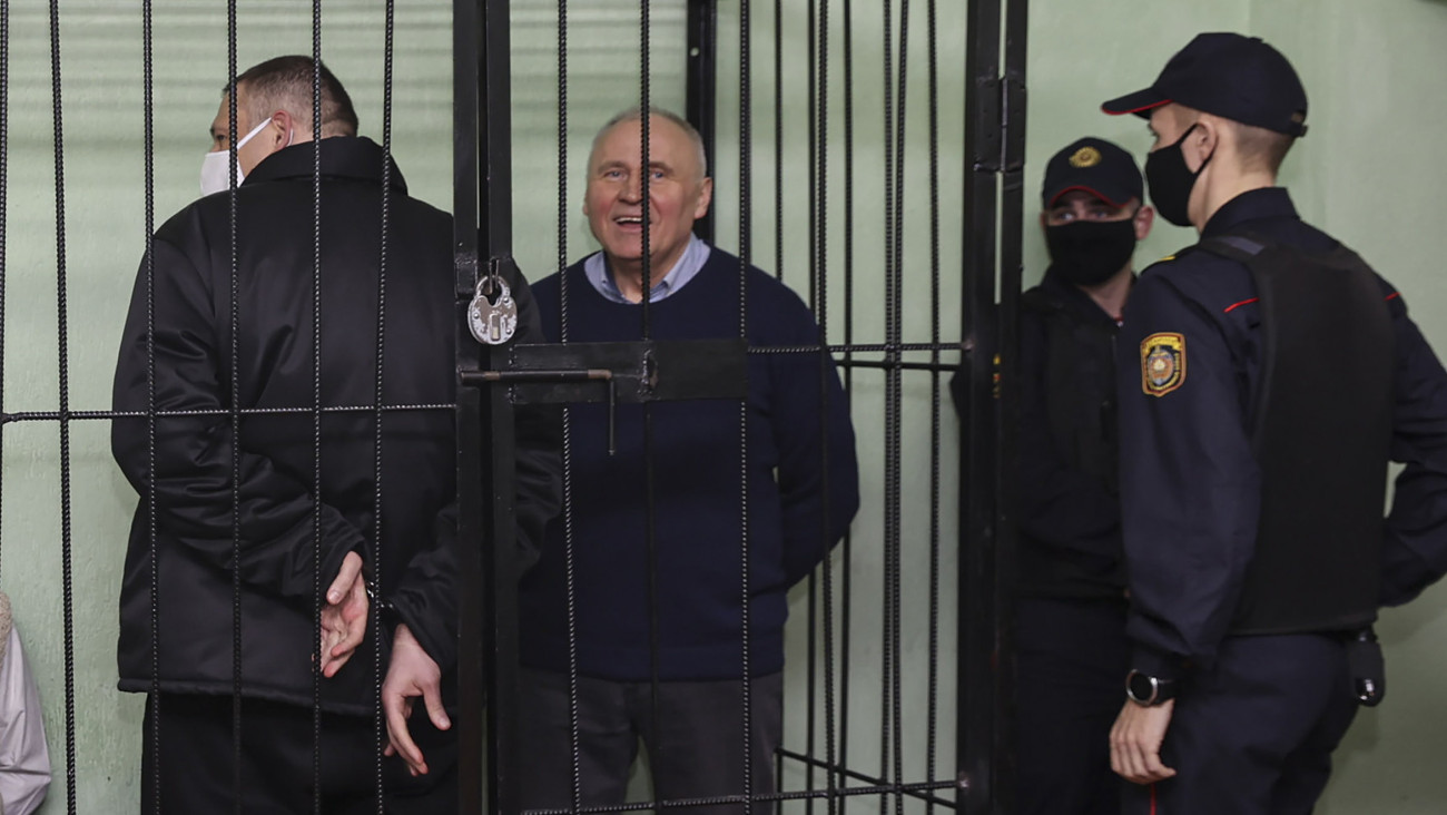 A BelTa fehérorosz állami hírügynökség által közreadott kép Szjarhej Cihanouszki népszerű kormányellenes aktivistáról és videobloggerről, az emigrációban élő ellenzéki vezetőnek, Szvjatlana Cihanouszkajának a férjéről (b) és Mikola Sztatkevics ellenzéki vezetőről (b2) a vádlottak cellájában perük ítélethirdetésén, Homelben 2021. december 14-én. Cihanouszkit egyebek között tömeges zavargásokra szóló felbujtás és gyűlöletkeltés miatt 18 év börtönbüntetésre ítélték, Sztatkevics 14 évet kapott.