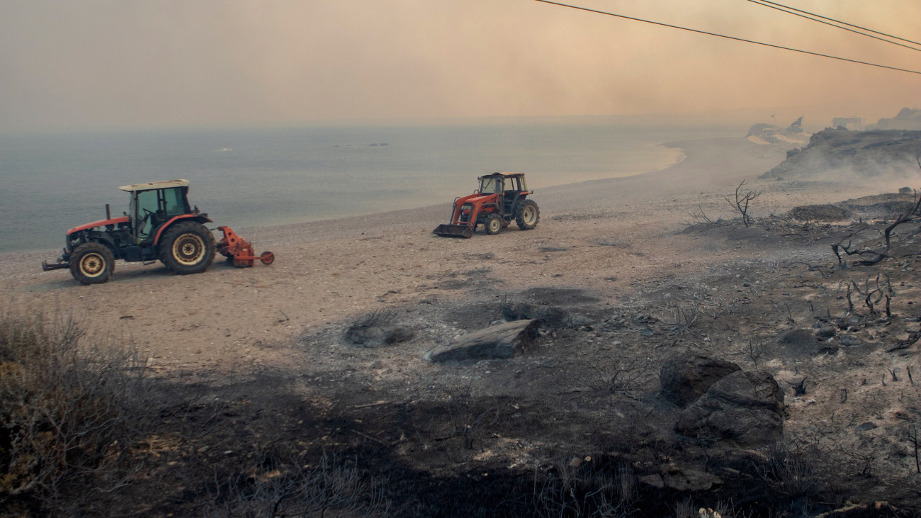 Traktorok vesznek részt a lángoló növényzet oltásában a Rodosz szigetén fekvő Kiotari falu határában 2023. július 22-én. A hőség és tartós csapadékhiány miatt Athén térségében is erdőtüzek pusztítanak.