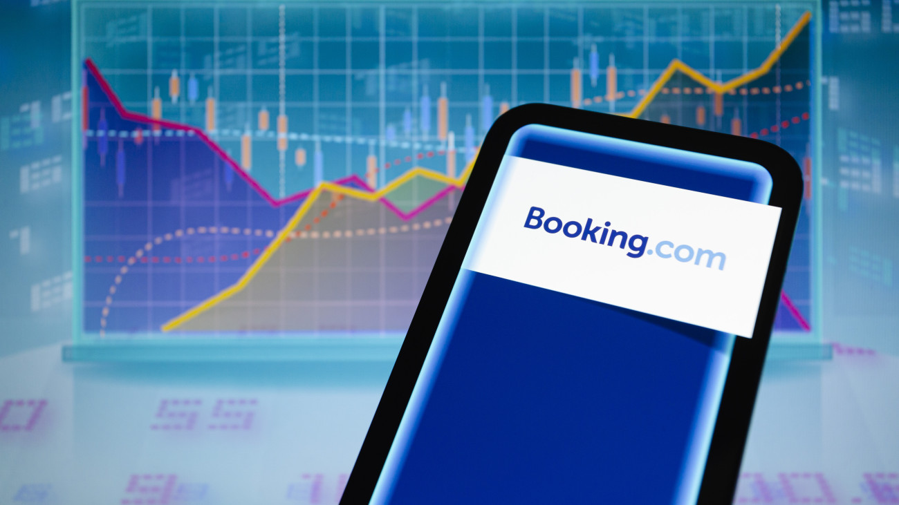 May 4, 2023, Asuncion, Paraguay: A view of the Booking.com logo is displayed on a smartphone backdropped by visual representation of stock and line charts.  LOGO BRAND SYMBOL