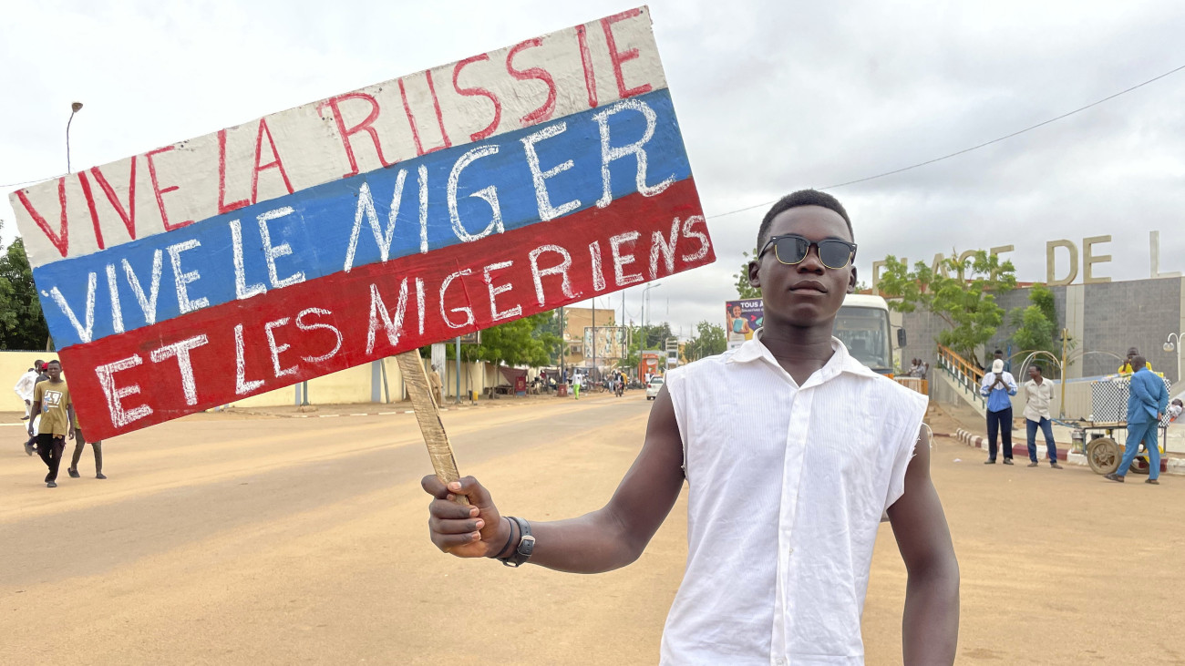 A puccsot végrehajtó Amadou Abdramane ezredes egyik támogatója az orosz zászló színeit viselő táblával a kezében Niger fővárosában, Niameyben 2023. augusztus 3-án. A táblán lévő felirat jelentése: Sokáig éljen Oroszország, sokáig éljen Niger és a nigeriek. Az afrikai országban katonai hatalomátvétel történt július 26-án.