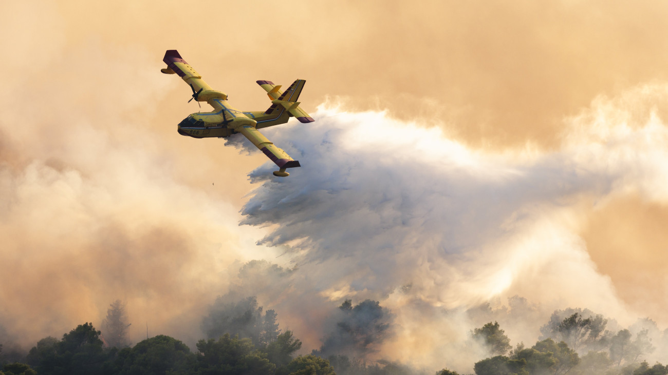 Tengervizet dob le a lángoló növényzetre egy hidroplán az erdőtűz sújtotta Ciovo horvát szigeten 2023. július 27-én. A lángok a sziget keleti térségében csaptak fel.