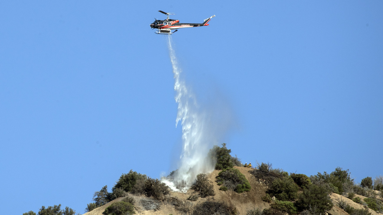 Vizet dob le egy tűzoltó helikopter a felperzselt növényzetre a kaliforniai Wrightwood település közelében, ahol erdőtűz pusztít 2022. június 13-án.