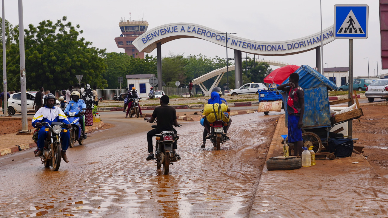 Motorkerékpárosok a niameyi repülőtér bejárata előtt 2023. augusztus 8-án. Augusztus 10-én a Nyugat-afrikai Államok Gazdasági Közössége (ECOWAS) a nigériai fővárosban, Abujában tanácskozást kezdett a nigeri válság további kezeléséről, miután a nigeri katonai junta ellenszegült a közösség által adott ultimátumnak, és nem helyezte vissza a hatalomba a megválasztott elnököt.