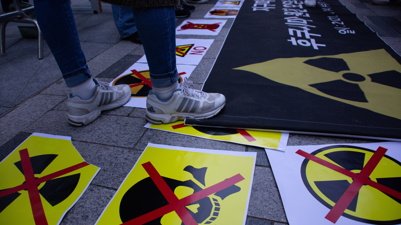 Környezetvédő aktivisták tüntetnek a japán nagykövetség épülete előtt Szöulban 2021. április 14-én. A tüntetők a japán kormány azon döntése ellen tiltakoznak, hogy a 2011-ben katasztrófát szenvedett fukusimai atomerőmű radioaktív elemeket tartalmazó, de már megtisztított hűtővizét az óceánba eresztik. Az erőművet működtető Tokyo Electric Power Co. (TEPCO) cég több mint egymillió tonna sugárszennyezett hűtővizet gyűjtött tartályokba a Fukusima I. atomerőmű területén azóta, hogy a 2011. március 11-i nagy erejű földrengést követő szökőár súlyosan megrongálta az erőmű három reaktorát.