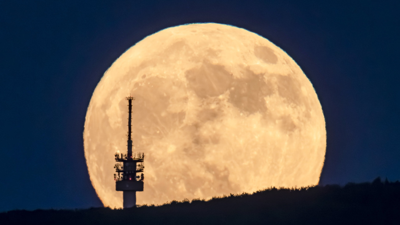 A felkelő Hold látszik a Galyatetőn lévő híradástechnikai torony mögött Mátraverebély közeléből fotózva 2023. június 3-án este.
