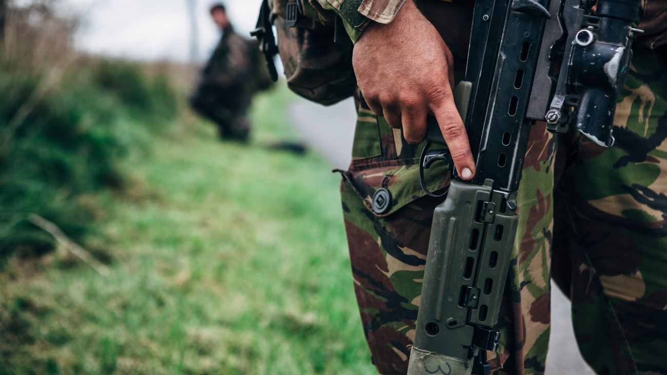 Close up view of a solider holding an L85A2 british assault rifle on a military training exercise in a rural location.