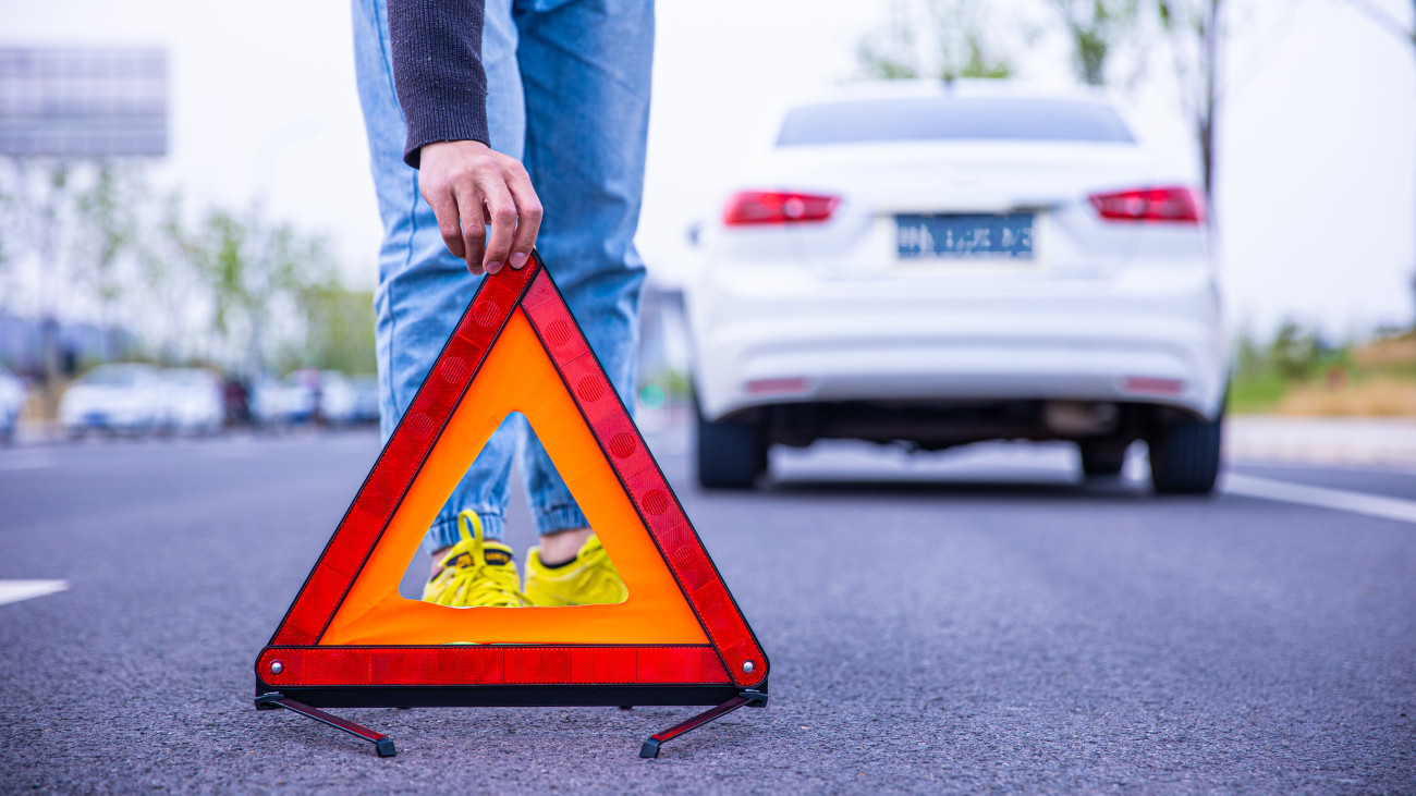 Man setting down red warning triangle; baleset lerobbant elakadásjelző háromszög