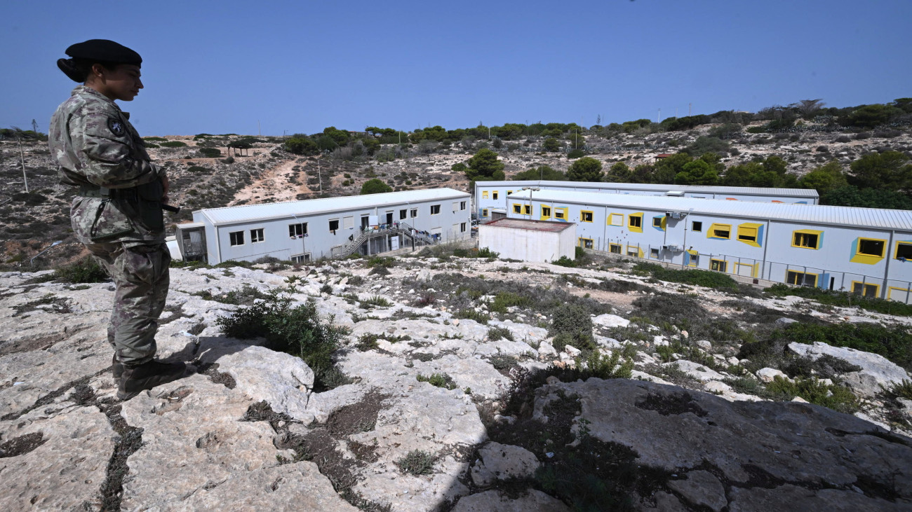 Az Európába igyekvő illegális bevándorlóknak létesített befogadóközpont fölötti dombon egy katonanő a dél-olaszországi Lampedusa szigetén 2023. szeptember 19-én. Az olasz kormány megszigorította az illegális bevándorlókra vonatkozó szabályokat, mert az előző évhez képest megkétszereződött az idén mostanáig Olaszországba érkezett migránsok száma.