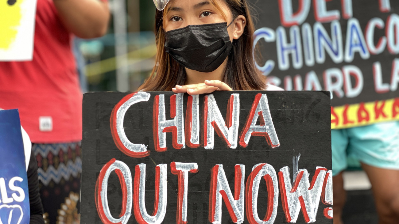 Kína távozását követeli egy tüntető nő a manilai kínai konzulátus előtt 2021. május 7-én. A tünetők az ellen tiltakoznak, hogy kínai halászhajók kínai járőrhajók kíséretében rendszeresen behatolnak a Fülöp-szigetek fennhatósága alatt álló területre a Dél-kínai-tengeren. Kína a nyersanyagokban gazdag, 3,5 millió négyzetkilométernyi Dél-kínai-tenger szinte egészét magának követeli, és katonai célra kiépített több mesterséges szigetet a vitatott területen. A világ egyik legforgalmasabb hajózási útvonalának számító tenger egyes részeit azonban a Fülöp-szigetek, Vietnam, Malajzia, Brunei és Tajvan is magáénak tartja.
