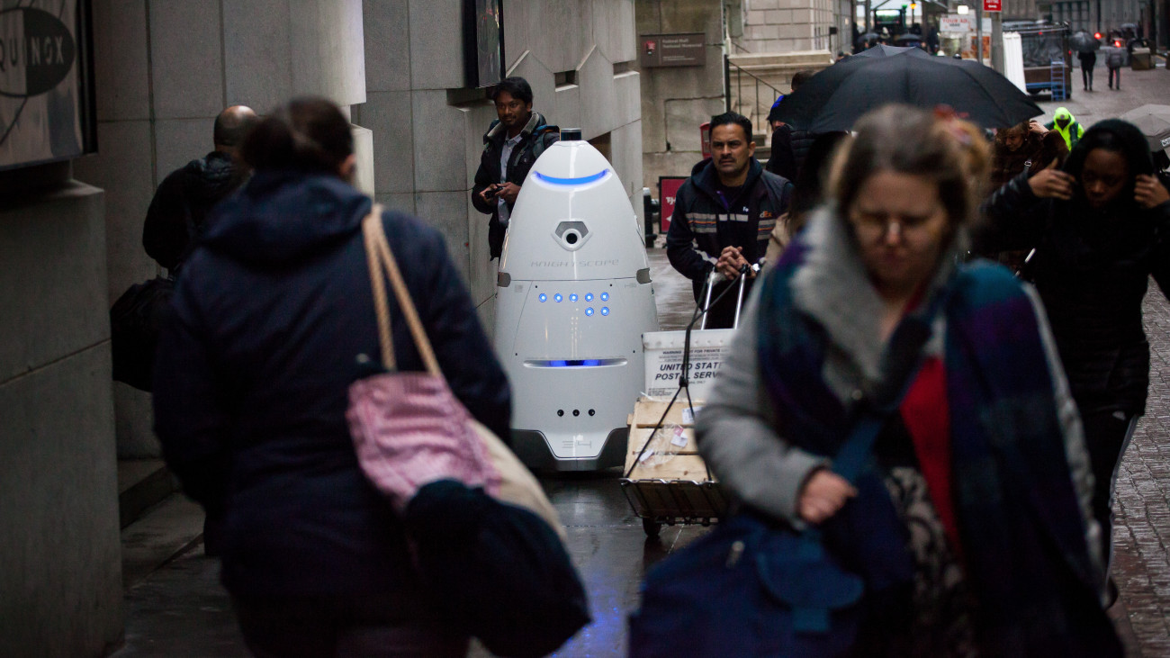 Pedestrians pass a Knightscope Inc. K5 security robot on Wall Street near the New York Stock Exchange (NYSE) in New York, U.S., on Tuesday, Jan. 17, 2017. U.S. stocks fell as markets reopened after Mondays holiday as financial and health-care shares declined and the U.S. dollar headed for the biggest single-day loss since July. Photographer: Michael Nagle/Bloomberg via Getty Images