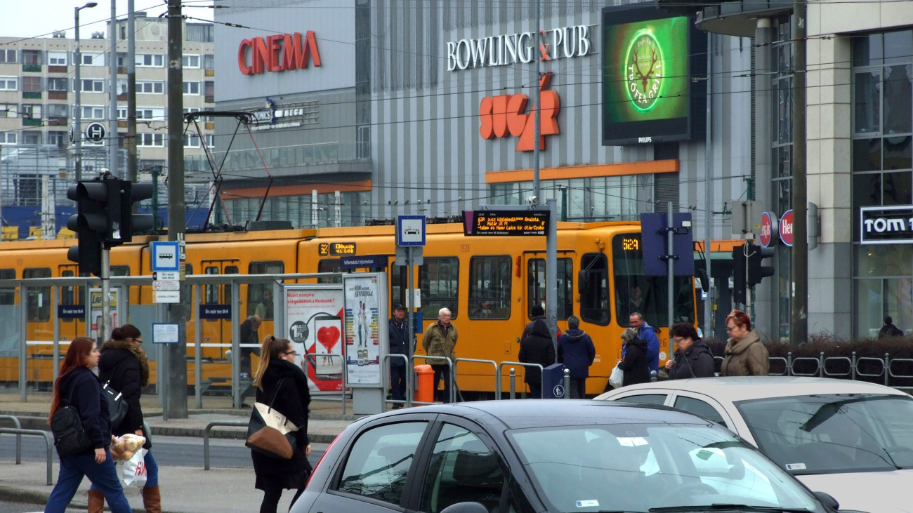 Budapest, 2016. február 18. A BKk-BKV 62A vonalán közlekedő hannoveri villamos indul a megállójából, valamint személygépkocsik haladtak át Zuglóból a X. kerületbe az Örs vezér terén. A zebrán gyalaogosok közlekednek, a háttérben pedig a Sugár üzletközpont  épülete látható a tér XIV. kerületi oldalán. MTVA/Bizományosi: Jászai Csaba