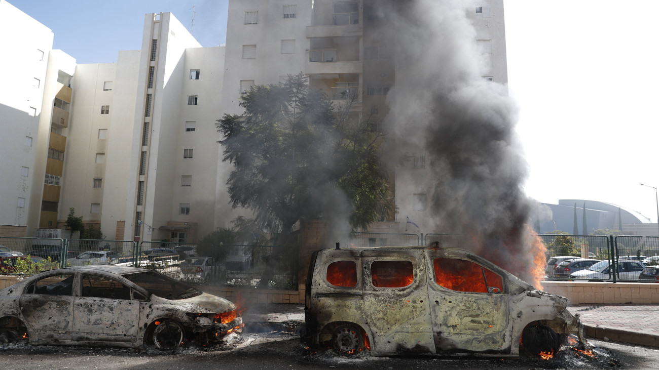 Palesztin rakétatámadásban kigyulladt járművek lángolnak az izraeli Askelonban 2023. október 7-én. A Hamász palesztin iszlamista szervezet reggel óta 2500 rakétát lőtt ki Izrael déli és középső részére a Gázai övezetből, és több tucat fegyverese hatolt be izraeli településekre. Eddig 22 halottról és félezer sebesültről tudni, a fegyveresek izraeli túszokat hurcoltak magukkal a Gázai övezetbe. Izrael teljes mozgósítást rendelt el.