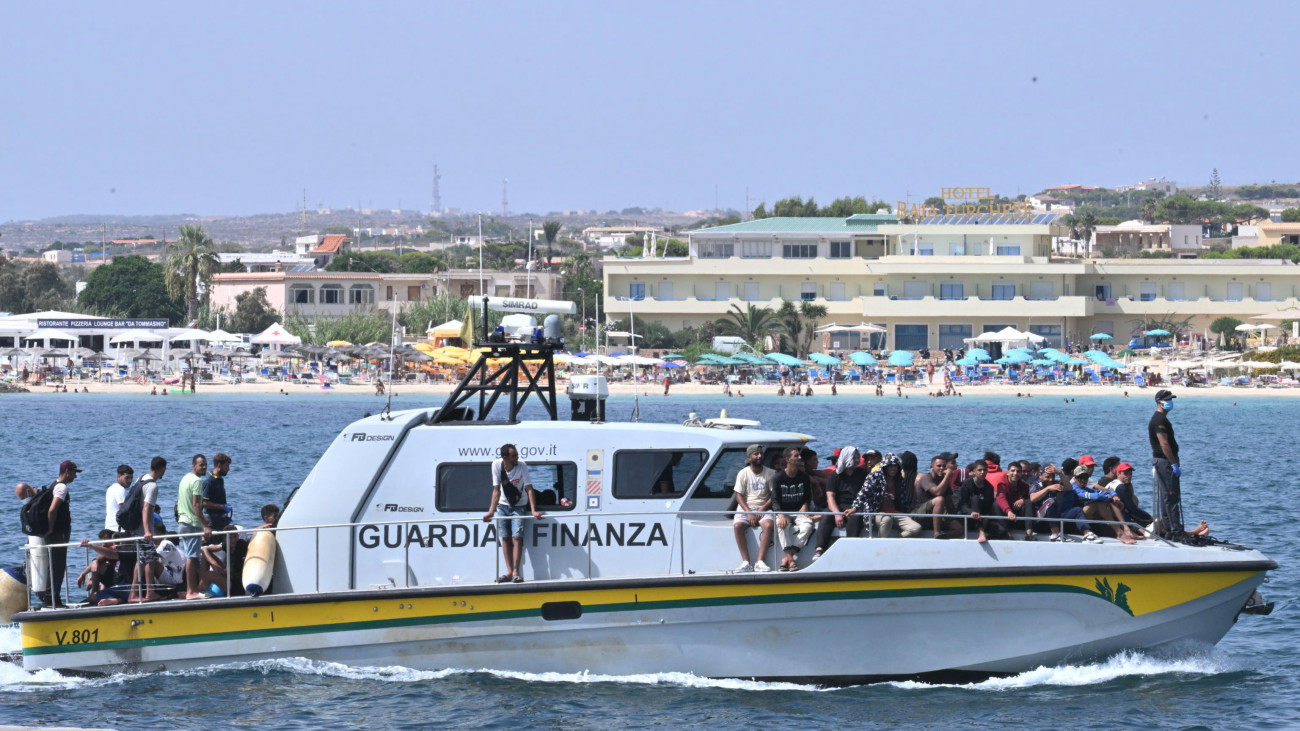 Illegális bevándorlók érkeznek az olasz pénzügyőrség hajóján a dél-olaszországi Lampedusa szigetére 2023. szeptember 19-én. Az olasz kormány megszigorította az illegális bevándorlókra vonatkozó szabályokat, mert az előző évhez képest megkétszereződött az idén mostanáig Olaszországba érkezett migránsok száma.