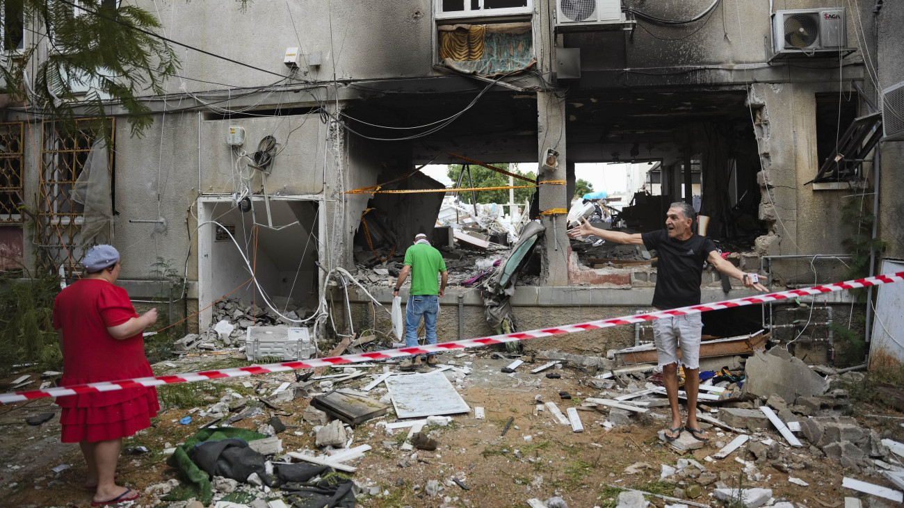 Palesztin rakétatámadásban megsérült lakóház előtt emberek a dél-izraeli Askelónban 2023. október 9-én. A Gázai övezetet irányító Hamász palesztin iszlamista szervezet október 7-én támadást indított Izrael ellen.