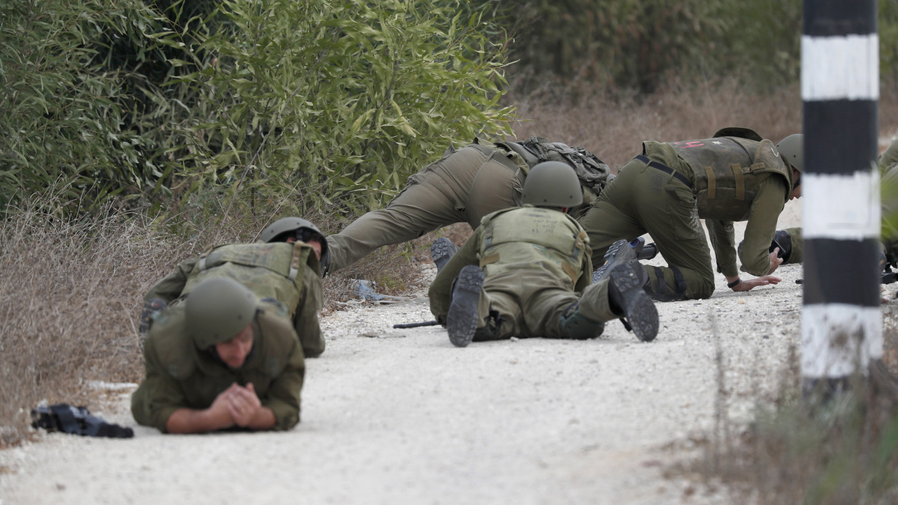 Izraeli katonák fedezékbe húzódnak egy palesztin rakétatámadás alatt az Izrael és a Gázai övezet határának térségében, Dél-Izraelben fekvő Szderót közelében 2023. október 9-én. A Gázai övezetet irányító Hamász palesztin iszlamista szervezet október 7-én többfrontos támadást indított Izrael ellen, több mint 700 izraeli életét vesztette, a Hamász elleni izraeli válaszcsapások halálos áldozatainak száma a Gázai övezetben 493.