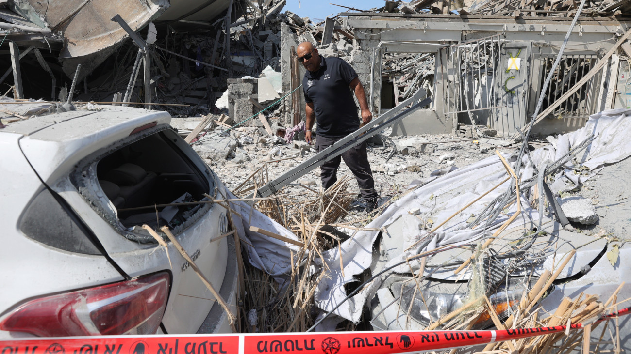Rendőr vizsgálja a romokat egy palesztin rakétatámadást követően Tel-Avivban 2023. október 8-án. Előző nap a Hamász palesztin iszlamista szervezet rakétaáradatot zúdított Izrael déli és középső részére a Gázai övezetből, és több tucat fegyverese hatolt be izraeli településekre. Az izraeli egészségügyi tárca október 8-i közlése szerint 2048 sebesültet szállítottak kórházba, akik közül az életveszélyes és súlyos sebesültek számát háromszázötvenre becsülik.