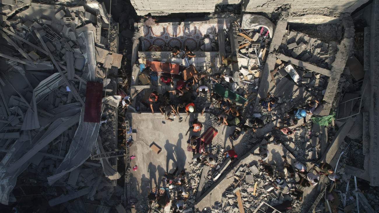 Áldozatokat keresnek a romok között palesztin férfiak egy izraeli légitámadás után a Gázai övezet nyugati részén fekvő Sati menekülttáborban 2023. október 12-én. A Gázai övezetet irányító Hamász palesztin iszlamista szervezet október 7-én többfrontos támadást indított Izrael ellen, több mint 1200 izraeli életét vesztette, a Hamász elleni izraeli válaszcsapások közel 1200 ember halálát okozták a Gázai övezetben.