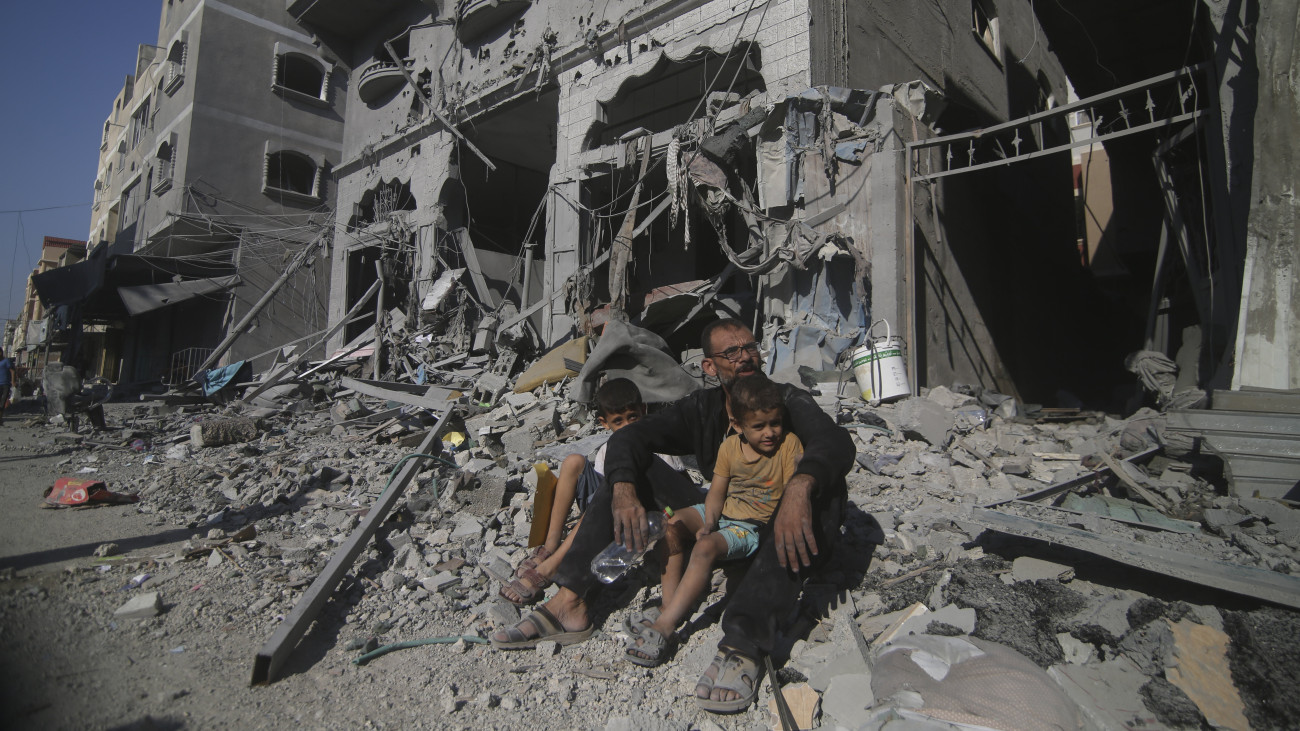 Izraeli légitámadások után a házuk előtt ülnek palesztinok a Gázai övezet déli részén fekvő rafahi menekülttáborban 2023. október 12-én. A Gázai övezetet irányító Hamász palesztin iszlamista szervezet október 7-én többfrontos támadást indított Izrael ellen, több mint 1200 izraeli életét vesztette, a Hamász elleni izraeli válaszcsapások közel 1200 ember halálát okozták a Gázai övezetben.