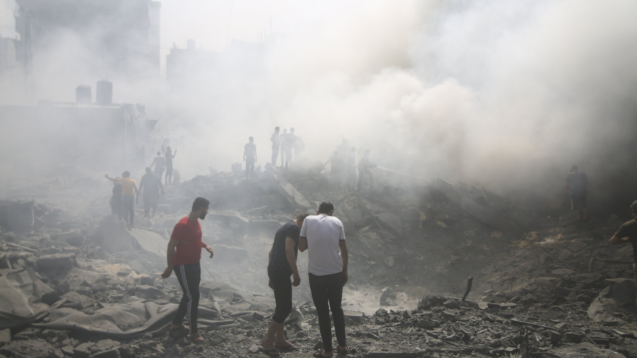 Áldozatokat keresnek a romok között palesztin férfiak egy izraeli légitámadás után a Gázai övezet déli részén fekvő rafahi menekülttáborban 2023. október 12-én. A Gázai övezetet irányító Hamász palesztin iszlamista szervezet október 7-én többfrontos támadást indított Izrael ellen, több mint 1200 izraeli életét vesztette, a Hamász elleni izraeli válaszcsapások közel 1200 ember halálát okozták a Gázai övezetben.