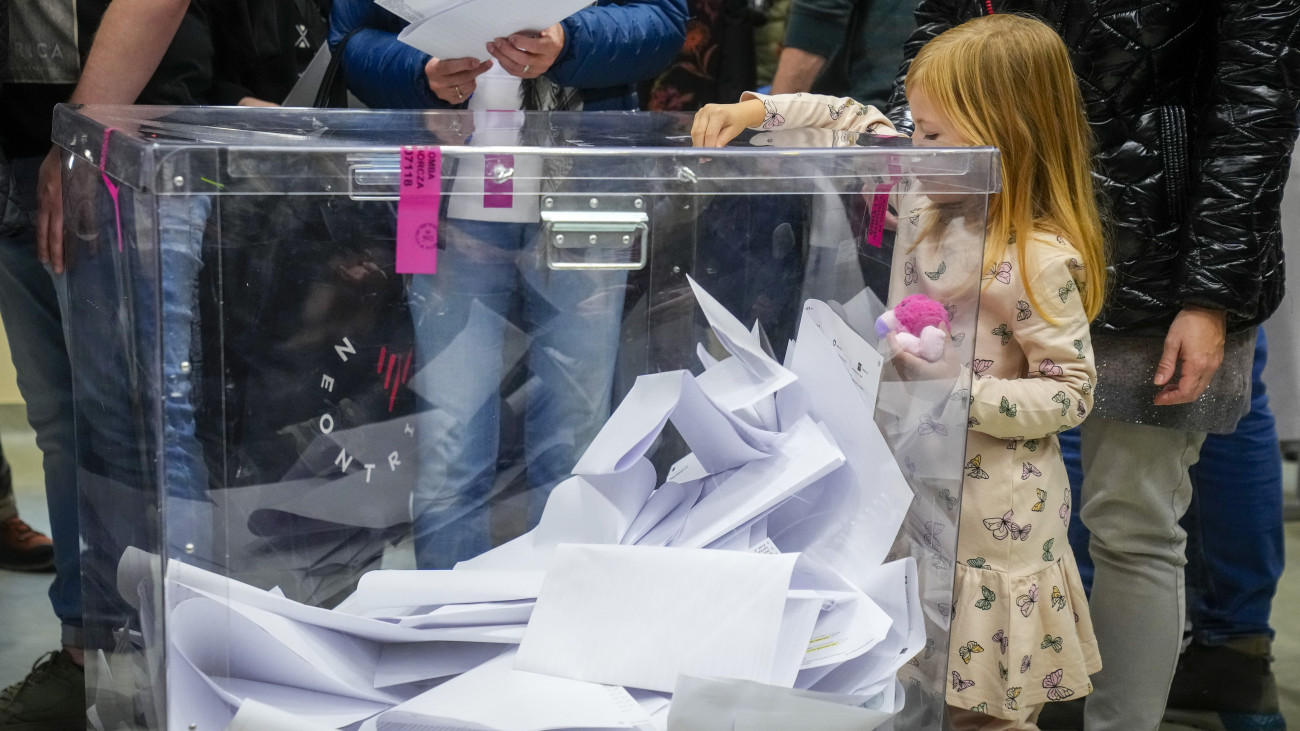 Kislány dob be szavazólapot a lengyel parlamenti választásokon Varsóban 2023. október 15-én. A választásokkal egy időben népszavazást is rendeznek az Európai Unió migrációs csomagjáról, az állami vagyon privatizációjáról, a nyugdíjkorhatárról, valamint a fehérorosz határon emelt acélkerítésről.