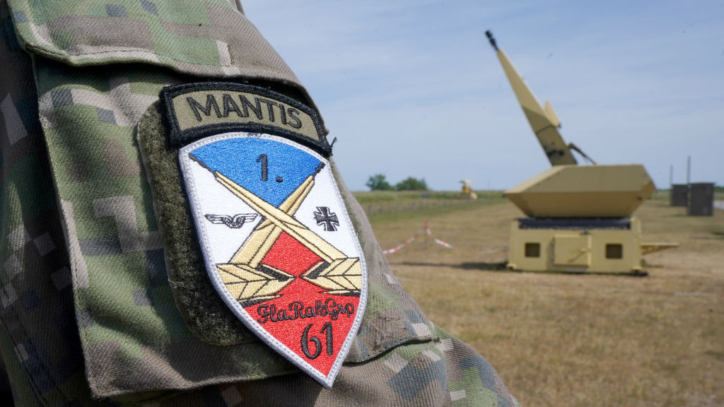31 May 2023, Schleswig-Holstein, Todendorf: The emblem of the Luftwaffes anti-aircraft missile group 61 can be seen on a soldiers sleeve next to a gun of the Mantis (Modular, Automatic and Network Capable Targeting and Interception System) anti-aircraft weapon system at the Todendorf training area. Until the end of June, the Air Force is training soldiers from Slovakia on the Mantis air defense weapon system. According to the Air Force, the training of the 44 Slovakian soldiers serves to further strengthen NATOs eastern flank. The system can be used to protect facilities and infrastructure from rocket and artillery fire as well as mortars. Photo: Marcus Brandt/dpa (Photo by Marcus Brandt/picture alliance via Getty Images)