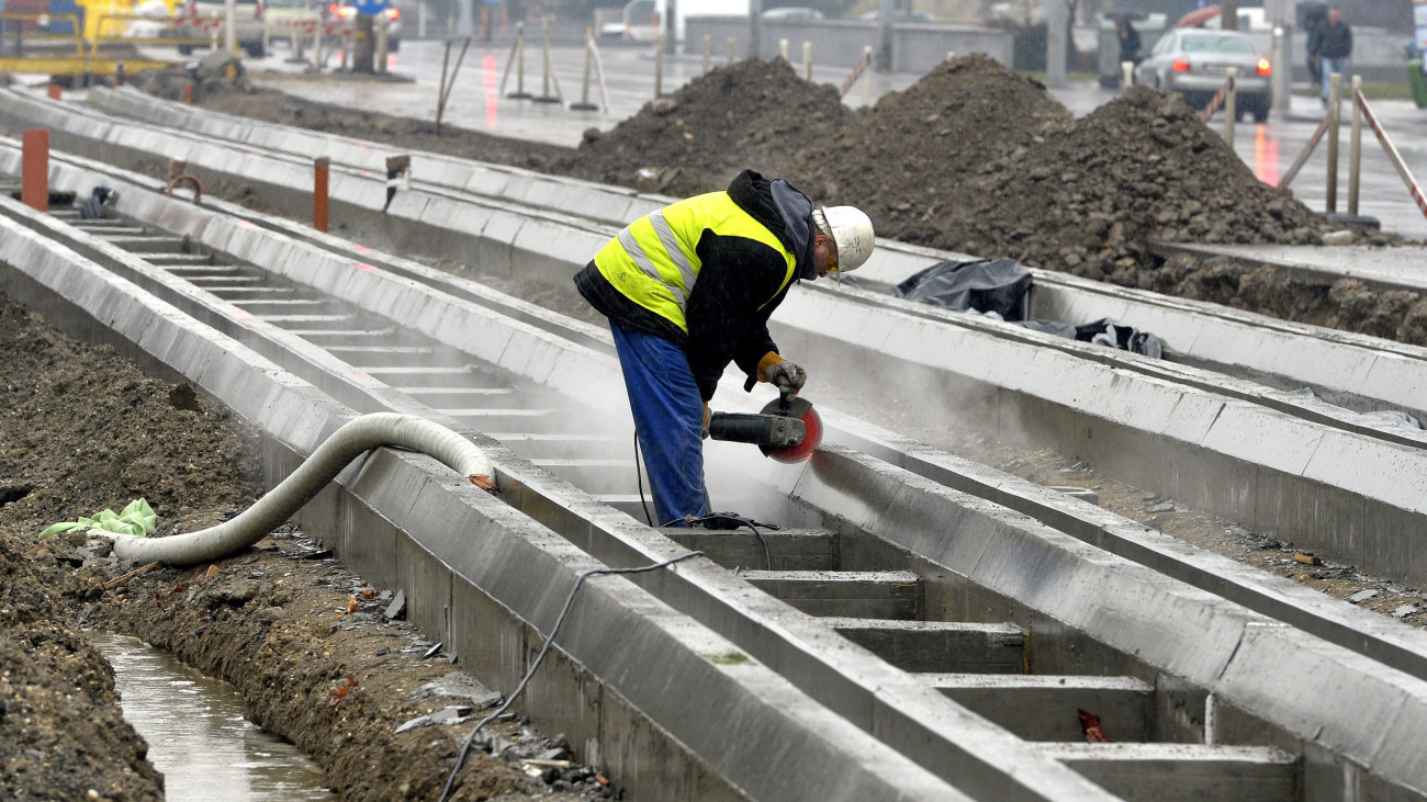 Egy munkás betont vág a felújítás alatt álló 1-es villamosvonal Vörösvári úti pályaszakaszán Budapesten 2014. február 11-én.