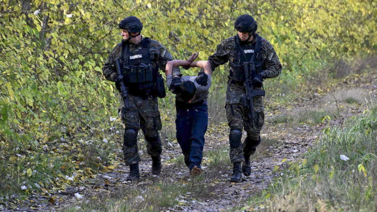 A szerb belügyminisztérium által közreadott felvételen szerb rendőrök elvezetnek egy őrizetbe vett migráns férfit a magyar határnál levő Horgosnál 2023. október 29-én. A szerbiai hatóságok több száz rendőrt vezényeltek a Magyarországgal közös határszakaszra azt követően, hogy október 27-én hajnalban lövöldözés tört ki migránsok között Horgosnál. A három halálos áldozatot követelő incidenssel összefüggésben hat migránst állítottak elő, négyen afgán, ketten török állampolgárnak vallották magukat. A szerb-magyar határ mentén több ezer migráns vár arra, hogy átszökhessen az Európai Unióba.