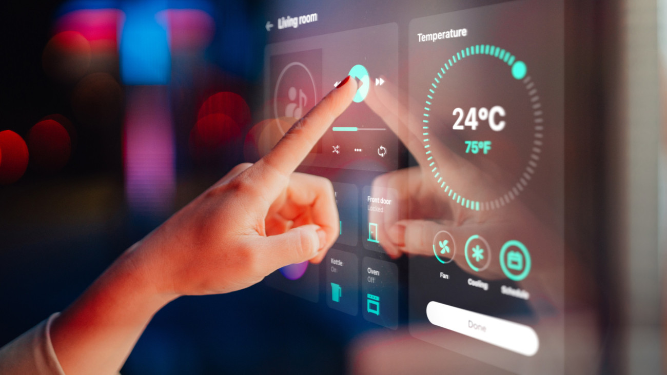 Close-up shot of a woman hand controlling smart home appliances with control panel in the living room of a modern home. Smart home technology concept. Smart living. Lifestyle and technology. Smart home dashboard - using a control panel of a modern smart home.