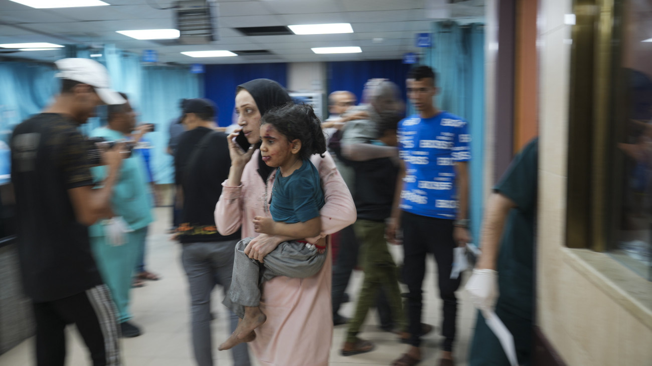 Izraeli légicsapásban megsebesült kislányával érkezik kórházba egy palesztin nő a Gázai övezet középső részén fekvő Deir al-Balahban 2023. október 21-én. A Gázai övezetet irányító Hamász palesztin iszlamista terrorszervezet október 7-én betört az övezet melletti izraeli településekre, ahol meggyilkoltak több mint 1400 embert, háromezret megsebesítettek és elhurcoltak kétszáz civilt. A Hamász elleni izraeli hadművelet eddig közel 3800 palesztin halálát okozta a Gázai övezetben, a sebesültek száma meghaladja a 12 ezret.