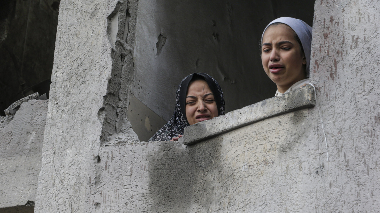Palesztin nők sírnak egy izraeli légicsapásban megrongálódott lakóház ablakában a Gázai övezet déli részén fekvő Rafahban 2023. november 20-án. A Hamász palesztin iszlamista szervezet fegyveresei október 7-én támadást indítottak Izrael ellen, az izraeli haderő pedig válaszul légi és szárazföldi hadműveleteket hajt végre a Gázai övezetben.