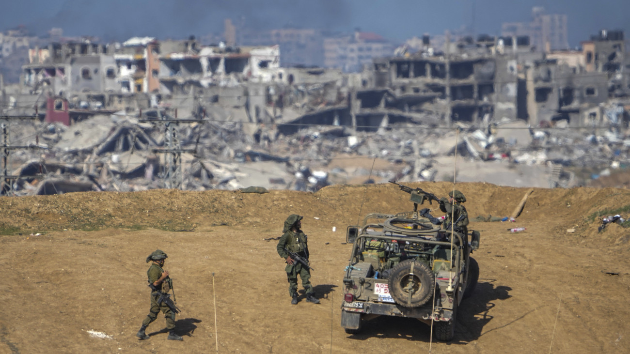 Izraeli katonák a Gázai övezet megsemmisült házainak romjai közelében Dél-Izraelben 2023. december 24-én. A Hamász palesztin iszlamista szervezet fegyveresei október 7-én támadást indítottak Izrael ellen, az izraeli haderő pedig válaszul légi és szárazföldi hadműveleteket hajt végre a Gázai övezetben.
