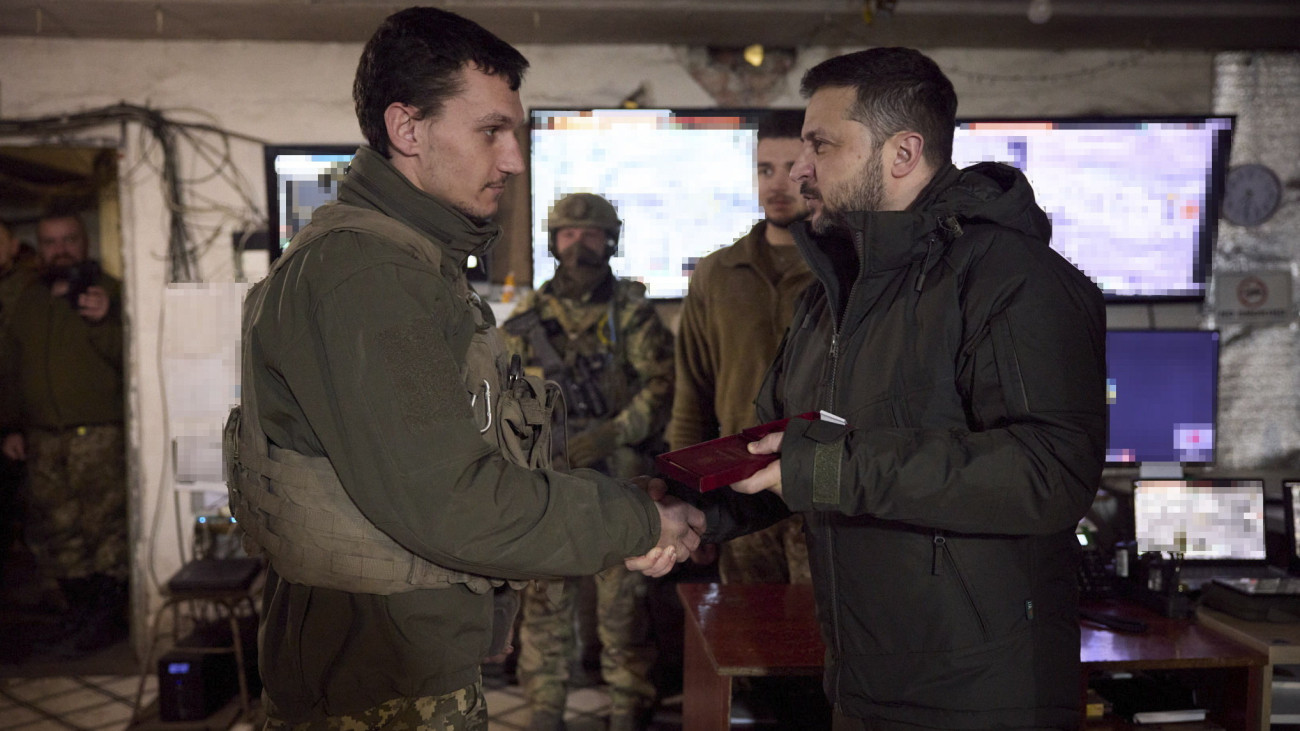 Az ukrán elnöki sajtószolgálat által közreadott képen Volodimir Zelenszkij ukrán elnök (k) kitüntetést ad át egy katonának a frontvonalon fekvő kelet-ukrajnai Avgyijivkában 2023. december 29-én. Avgyijivkát az orosz erők hónapok óta ostromolják és próbálják körülzárni.