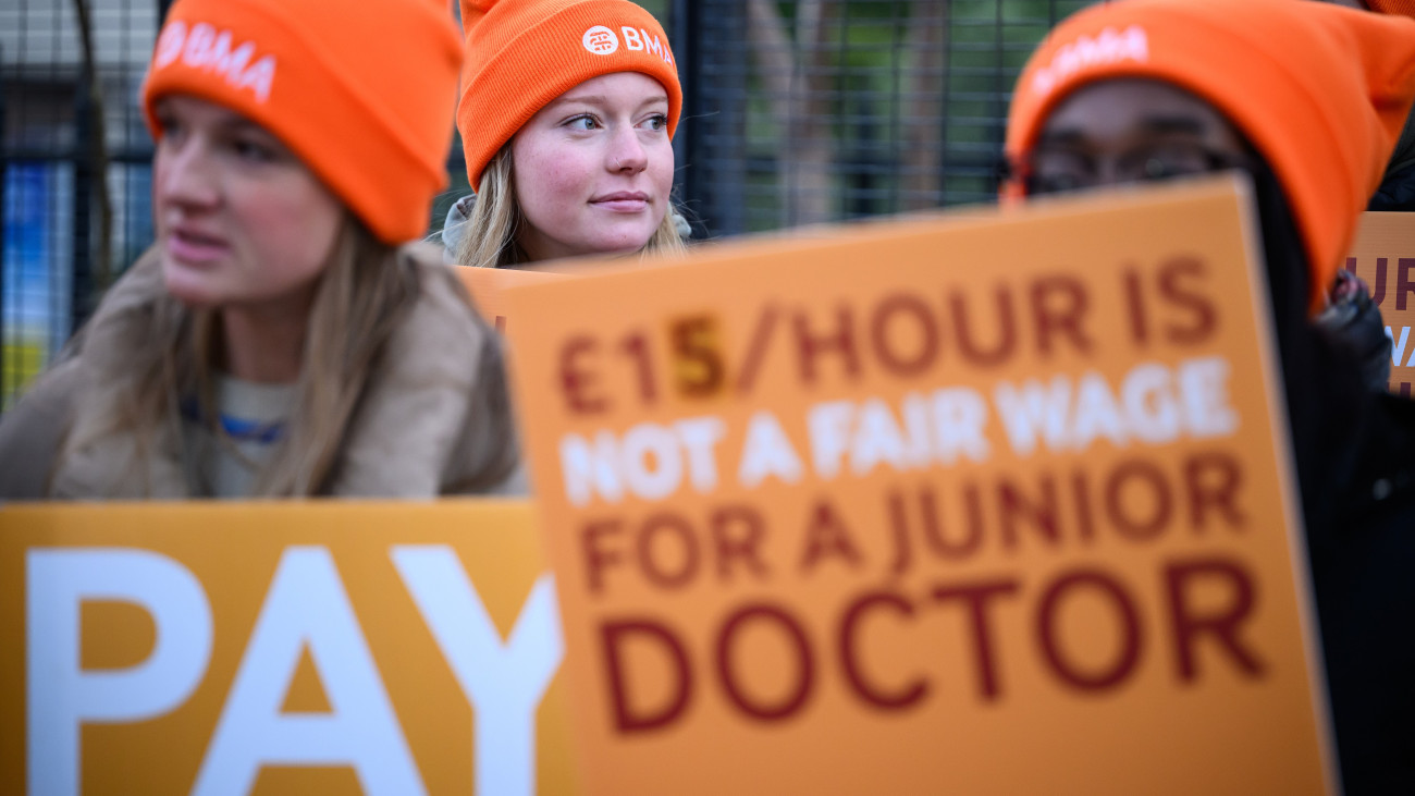 LONDON, ENGLAND - JANUARY 03: Young doctors and supporters hold placards as they gather outside St Thomas hospital at the start of their 6-day strike over pay, on January 03, 2024 in London, England. The junior doctors strike, set to last until 7 am on Tuesday, January 9, is the longest consecutive strike in NHS history. It follows a three-day industrial action in December 2023, driven by an ongoing pay dispute with the government. (Photo by Leon Neal/Getty Images)