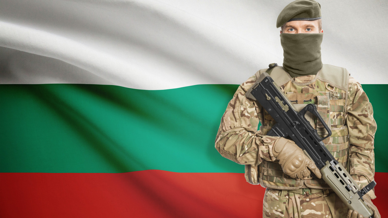 Soldier holding machine gun with national flag on background - Bulgaria