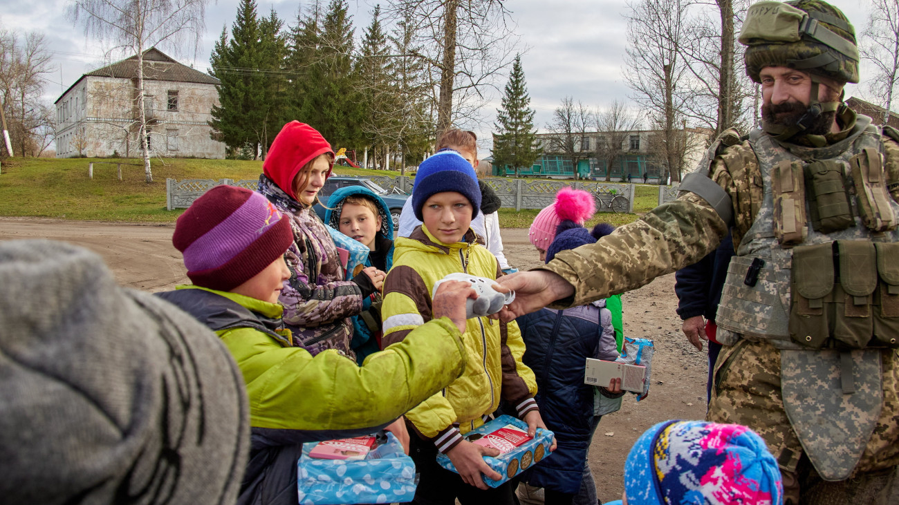 Ukrán katona édességet és játékokat ajándékoz gyerekeknek a kelet-ukrajnai Harkiv közelében fekvő, az orosz hadseregtől a közelmúltban visszafoglalt Kupjanszkban 2022. november 7-én.
