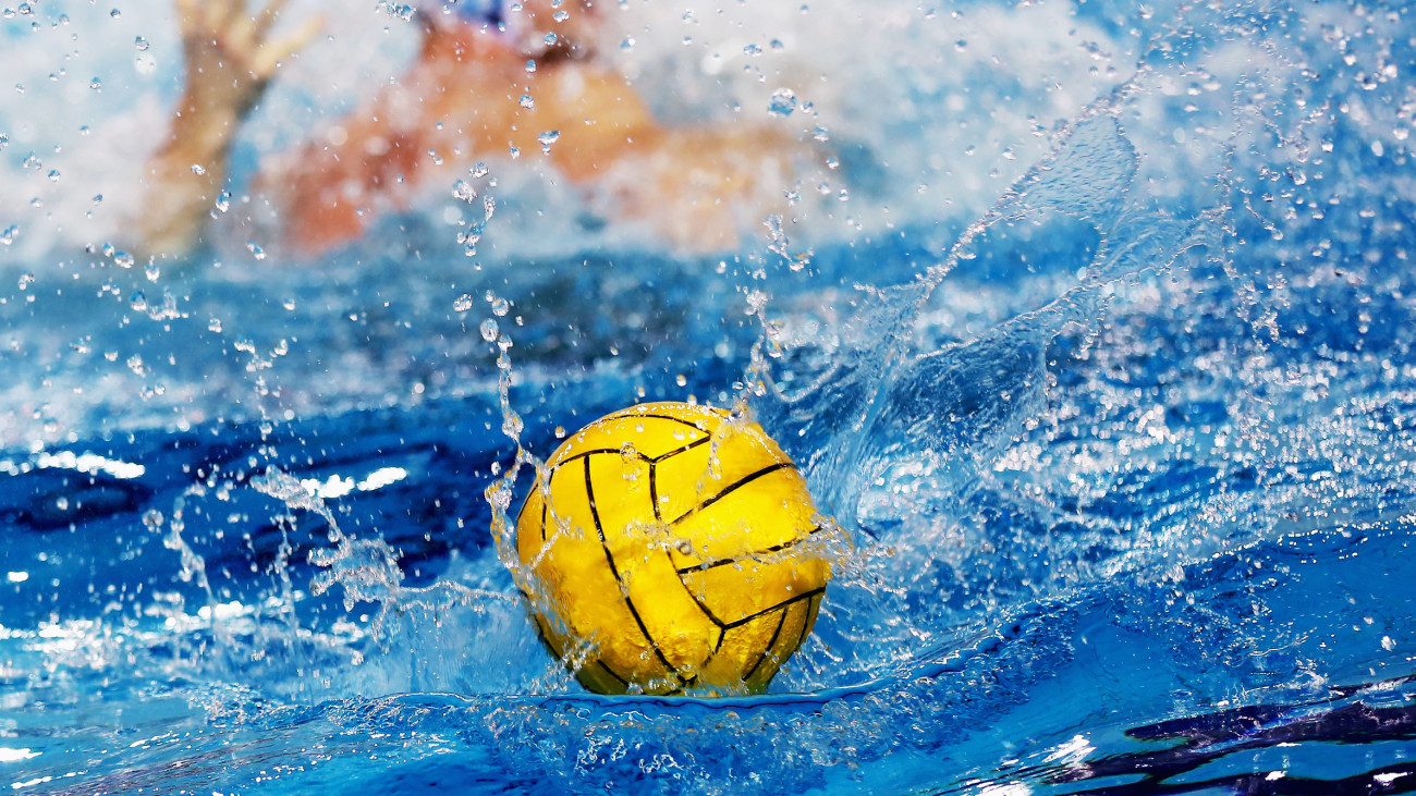 Yellow Water Polo Ball falling into the water with splashing effect against blurred sportsman background, natural lighting, copy space