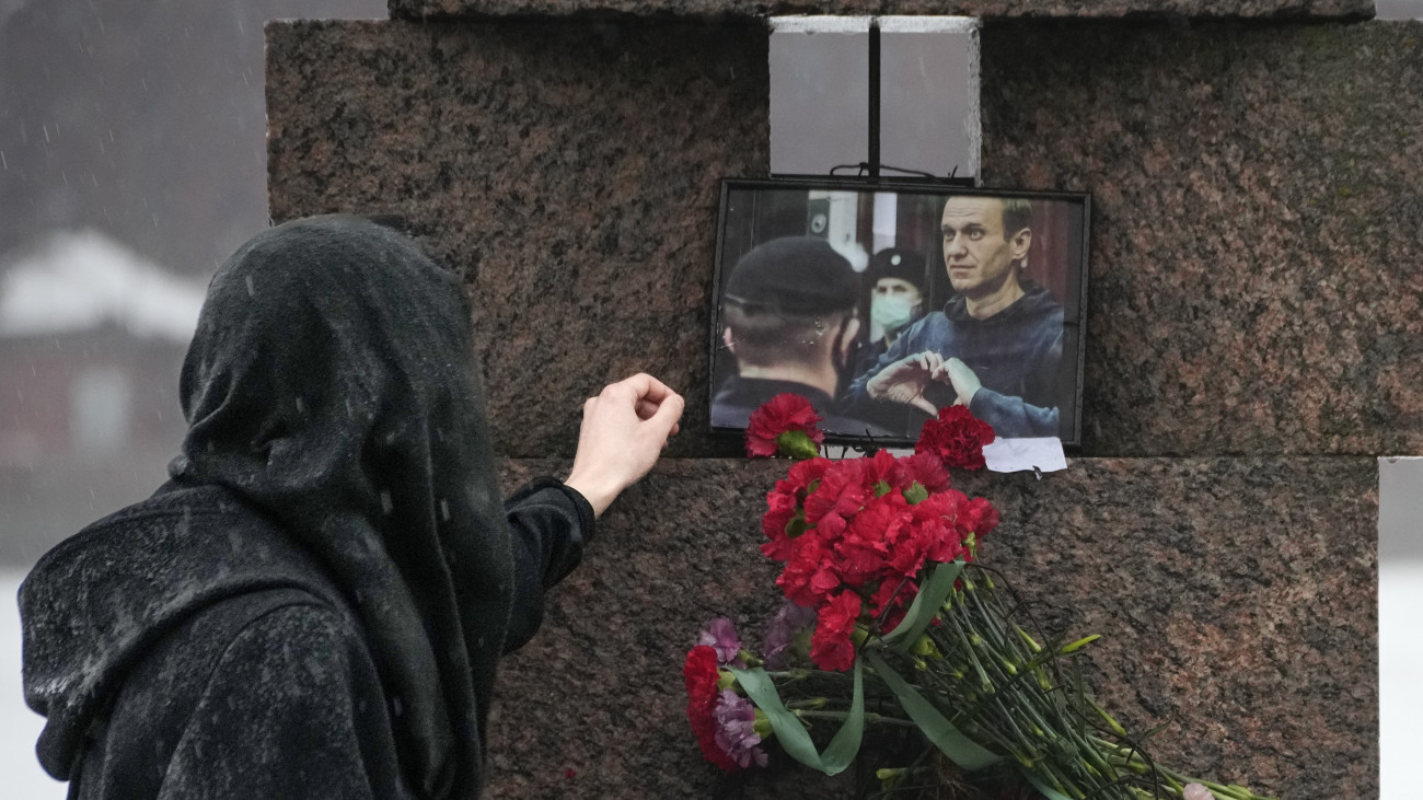 Alekszej Navalnij orosz ellenzéki politikus fényképét érinti meg egyik tisztelője a politikai elnyomás áldozatainak szentpétervári emlékművénél 2024. február 17-én. Az orosz hatóságok bejelentették, hogy a börtönbüntetését töltő Navalnij február 16-án, 47 éves korában elhunyt.