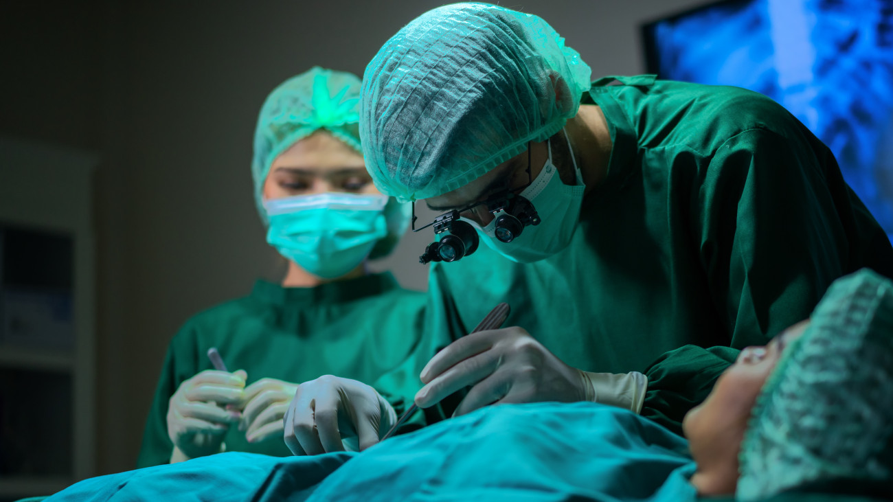 Surgeons operating patient for breast implant. Team of doctors are in scrubs at operating room.